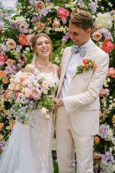 a bride and groom standing in front of a floral arch