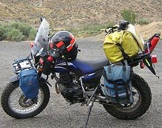 the motorcycle is parked on the side of the road with its luggage strapped to it's back