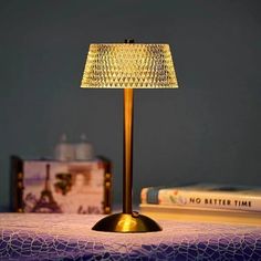 a table lamp sitting on top of a bed next to a stack of books and a book bag