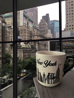 a coffee cup sitting on top of a window sill in front of a cityscape