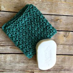 a green crocheted cloth next to a white soap bar on a wooden surface