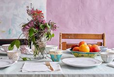 the table is set with plates, cups, and bowls full of fruit on it