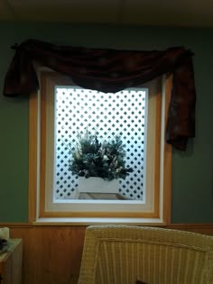 a chair and window in a room with green walls, white latticed wall and brown curtains