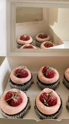 cupcakes with pink frosting and strawberries in a box