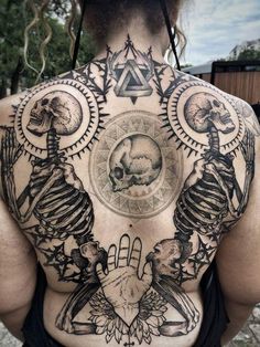 the back of a man with tattoos on his body and two skulls in front of him