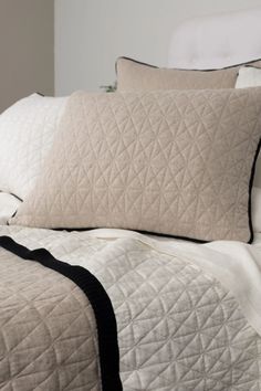 a bed with white and black quilts on it's headboard, along with two pillows