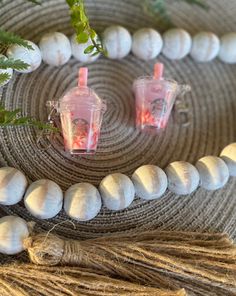 two plastic cups sitting on top of a rope next to some beads and plants in front of them