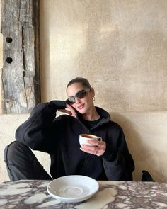 a woman sitting at a table with a cup of coffee