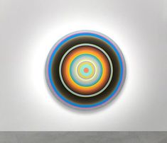 an abstract painting on a white wall with blue, yellow and red circles in the center