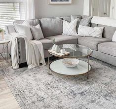 a living room with gray couches and white pillows on the sofa, along with a coffee table