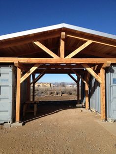 an outdoor covered area with storage containers and a wooden roof over the entrance to it