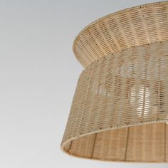 a wicker lamp hanging from the ceiling with a white wall in the back ground