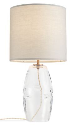 a clear glass table lamp with a white shade on the base and a beige cord attached to it