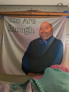 a man is smiling in front of a banner that says you are enough on it