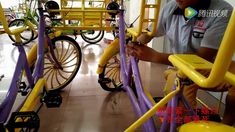 a man working on some kind of bike in a building with other bikes behind him