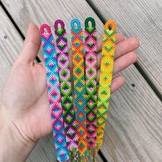 a person holding four colorful bracelets in their hand