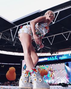 a woman standing on top of a stage with her legs spread out in front of her