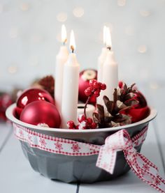 a bowl filled with christmas decorations and candles