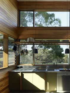 a kitchen with wooden walls and flooring next to a window that looks out onto the outdoors