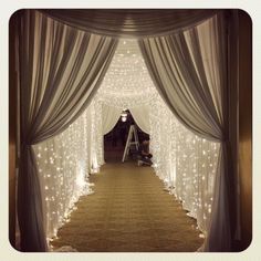 an aisle decorated with white lights and drapes