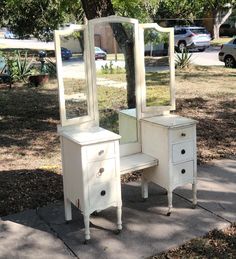 an old dresser and mirror are sitting on the sidewalk in front of a tree with no leaves