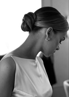 a woman in a white dress looking down at her cell phone while wearing earrings