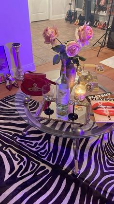 a glass table topped with pink roses on top of a zebra print rug