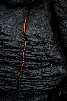 lava flowing down the side of a mountain, with red and orange flames coming out of it