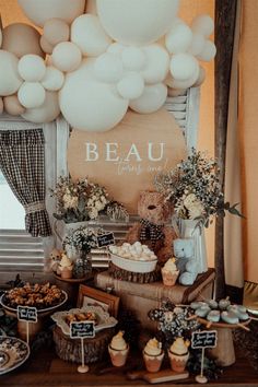 the dessert table is set up with white balloons