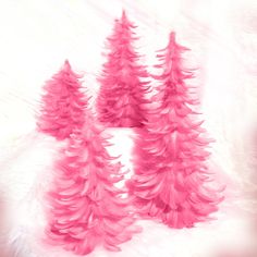 three pink christmas trees on a white background with fluffy fur around them and one is in the foreground