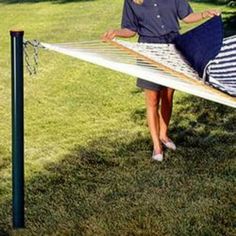 a woman standing next to a hammock in the grass