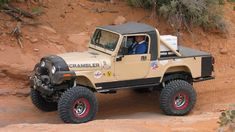 a jeep driving down a dirt road next to a cliff