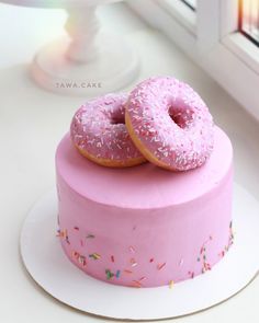 two donuts are on top of a pink cake