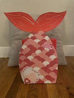 a paper bag with a red leaf on it sitting on top of a wooden floor