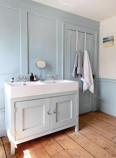 a bathroom with blue walls and two sinks in the center, one has a white towel hanging from it's hooks