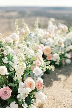 wedding flowers lined up in rows on the beach