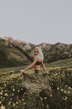 a woman is standing in a field with flowers