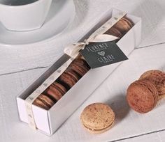 a box of chocolate covered cookies next to a cup of coffee on a white table