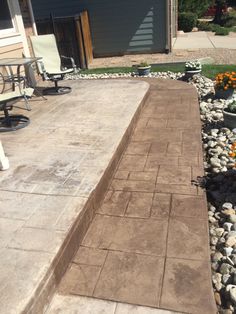 an empty patio with chairs and gravel in the foreground, next to a house