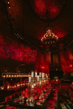 an elaborately decorated dining room with candles and chandeliers on the ceiling is lit by red lights