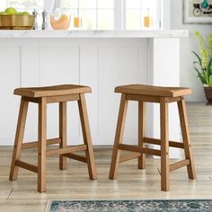 two wooden stools sitting in front of a kitchen counter with an area rug on the floor