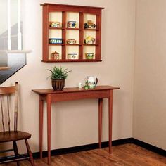 a small wooden table sitting in front of a wall mounted shelf with shelves on it