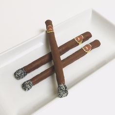 three cigars are arranged on a white plate