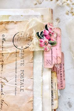 an old envelope with pink flowers on it and some paper tags attached to the side