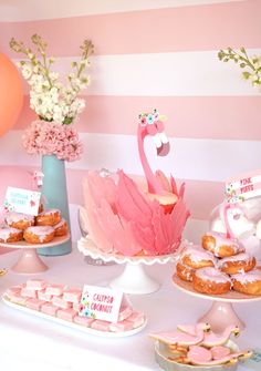 a pink flamingo themed dessert table with donuts and pastries on the table