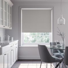 a dining room table and chairs in front of a window with roman shades on the windowsill