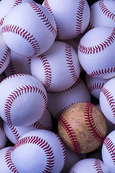 a pile of white baseballs with red stitching