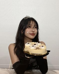 a woman in black gloves holding a cake with white frosting on it's face