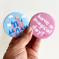 a hand holding two buttons that say have a magic day