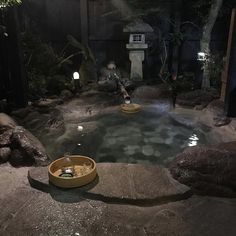 a small pool with some rocks around it and lights in the water on either side